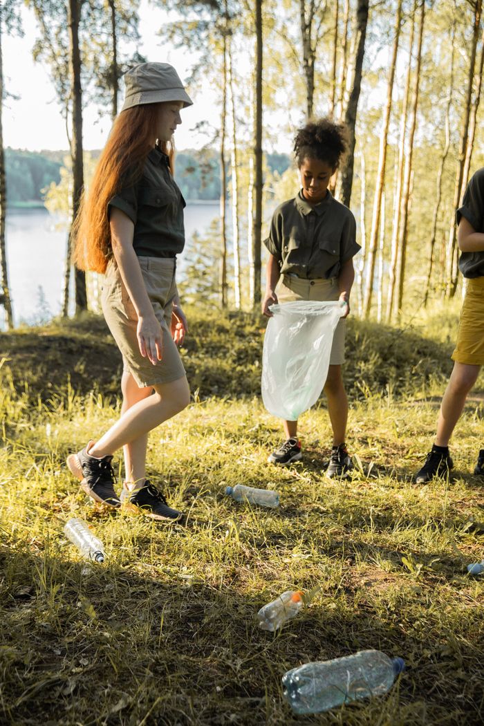 Services Kids collecting plastic waste in a forest, promoting environmental care.