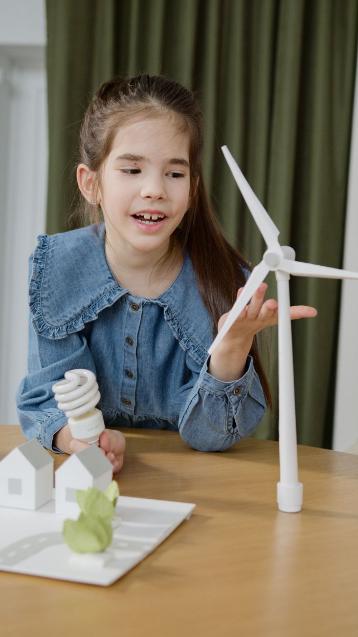 Services A young girl interacts with a wind turbine model, promoting sustainable energy awareness.