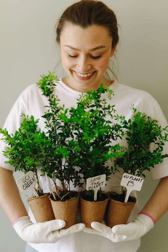 Services Smiling woman holding potted plants promotes sustainability and eco-friendly gardening.