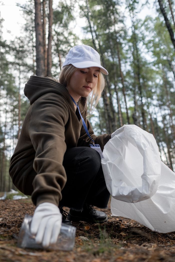 Services Woman participating in environmental cleanup in a forest, wearing warm clothing and protective gear.